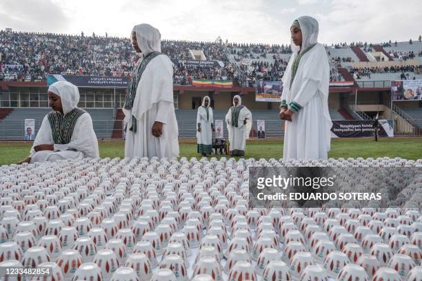 Women in traditional dresses stand next to a traditional coffee ceremony stall in a stadium in Jimma on June 16, 2021 for an electoral campaign rally...