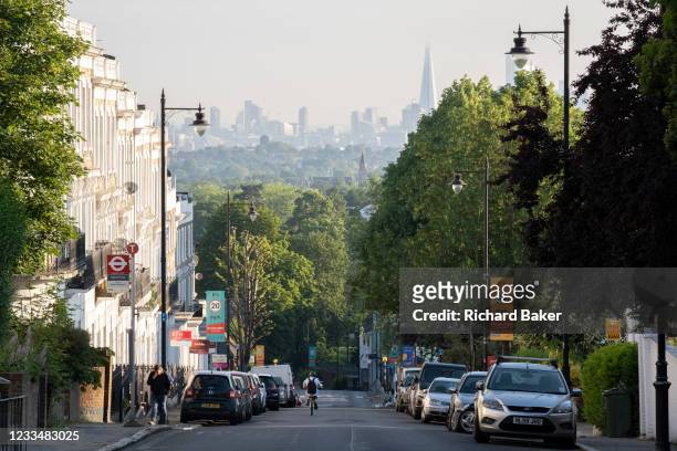 With the London skyline in the far distance, a cyclist descends the steep Gypsy Hill in Crystal Palace, on 16th June 2021, in London, England.