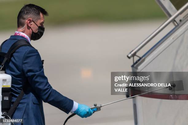 Security officer disinfects the stairs to be used to disembark by Russian President Vladimir Putin as he arrives at Cointrin airport ahead of his...