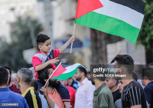 Palestinian boy carried on the shoulders of his father waves a flag, during a demonstration against the controversial flag march, organized by some...