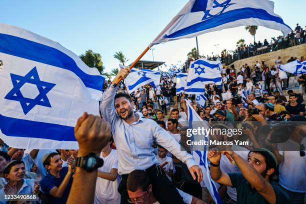 Bezalel Yoel Smotrich is hoisted up by far right Israelis as they danced and waved the national flag rally outside the Old CityÕs Damascus gate for...
