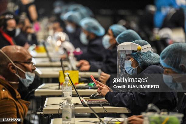 Health workers take data at a vaccination centre against covid-19 in Bogota, on June 16, 2021. - Colombia has officially recorded more than 90,000...