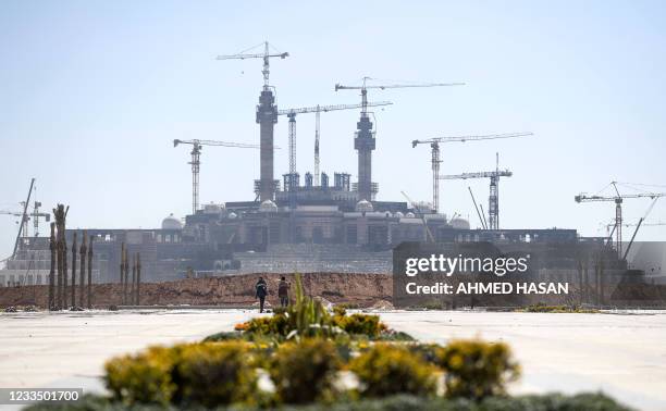 Workmen walk together while behind is seen ongoing construction at the site of the new "Grand Egyptian Mosque" being built at Egypt's "New...
