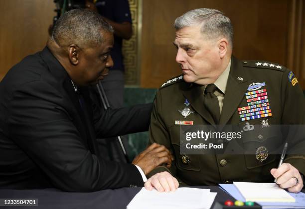 Defense Secretary Lloyd Austin talks with Joint Chiefs of Staff Chair Gen. Mark Milley as they are seated to testify on the Defense Department's...