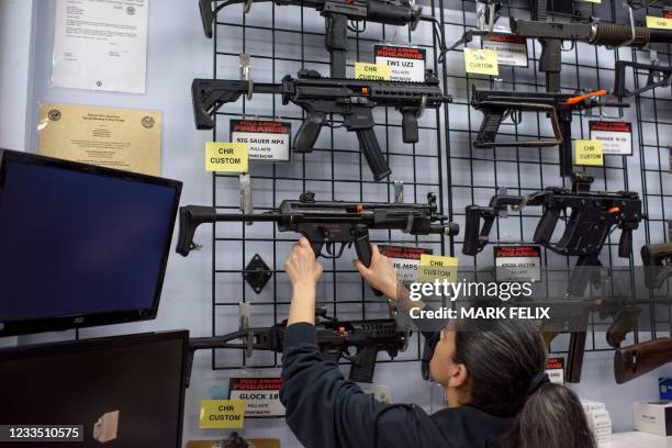 Employee Gorety Mejia takes down a HK MP5 for a customer at Full Armor Firearms store in Houston, Texas on June 17, 2021. - Governor Greg Abbott...