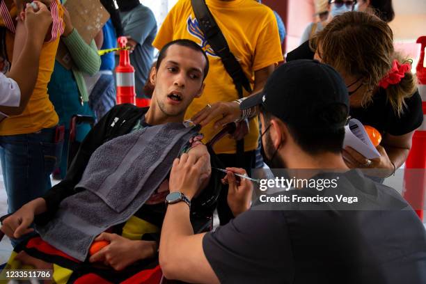 Health worker administers a dose of the COVID-19 vaccine to a citizen in a wheelchair at the mass vaccination center of the Universidad de Baja...