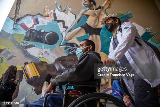 Citizen in a wheelchair is helped to arrive a vaccination center to receive the U.S. Donated Johnson & Johnson vaccine against Covid-19 at...