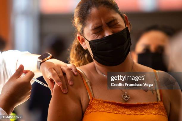 Health worker administers a dose of the COVID-19 vaccine to a citizen who reacts at the mass vaccination center of the Universidad de Baja California...