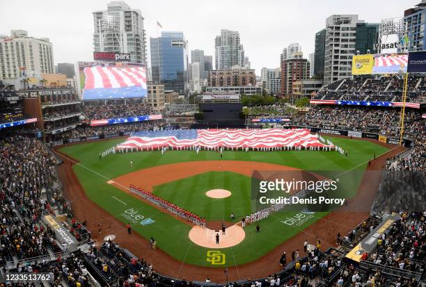 Navy sailors unveil an American flag before a baseball game between the Cincinnati Reds and the San Diego Padres at Petco Park on June 17, 2021 in...