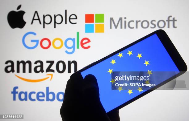 In this photo illustration, the EU flag is seen on a smartphone screen in front of Apple, Microsoft, Google, Amazon and Facebook logos.