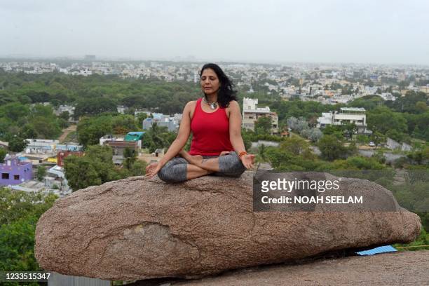 An instructor performs Yoga ahead of the International Yoga day atop rock formations overlooking the city at the Gun rock hills in Hyderabad on June...