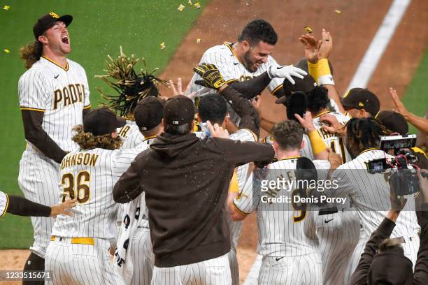 Victor Caratini of the San Diego Padres is greeted at the plate by teammates after hitting a walk-off, two-run home run in the ninth inning against...