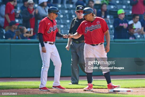 Josh Naylor of the Cleveland Indians celebrates with third base coach Mike Sarbaugh, after advancing to third base on a single by Rene Rivera in the...