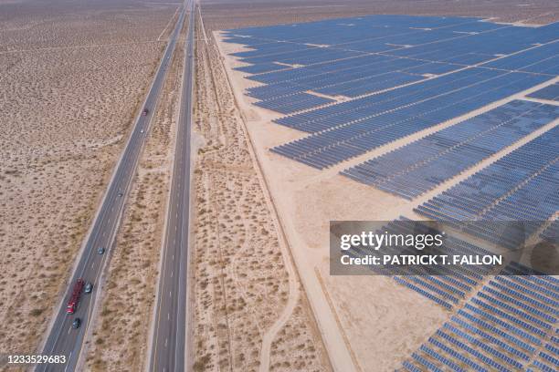 An aerial image shows vehicles driving on the California 14 Highway as solar panels, part of an electricity generation plant, stand on June 18, 2021...