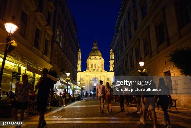 June 2021, Hungary, Budapest: Passers-by walk along a pedestrian street in front of St. Stephen's Basilica in the Pest district of the city in the...