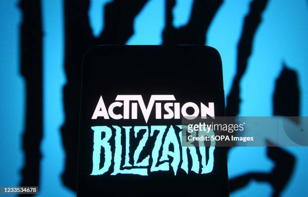 In this photo illustration, Activision Blizzard logo of a video game company is seen on a smartphone screen in front of Blizzard Entertainment logo.