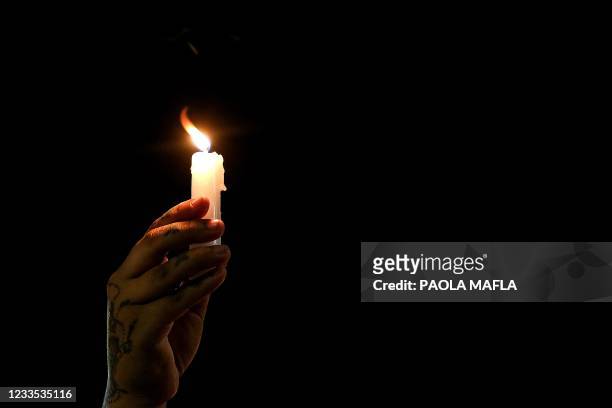 Person holds a lit candle as relatives and friends of Juan David Montenegro attend a vigil on June 18 in Cali, Colombia, after his death during...