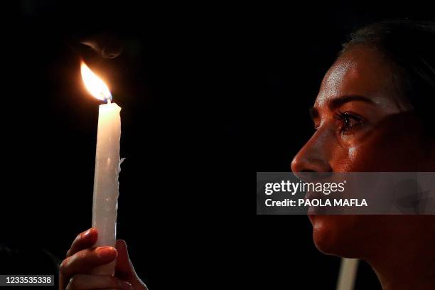 Woman holds a candle as relatives and friends of Juan David Montenegro attend a vigil on June 18 in Cali, Colombia, after his death during clashes...