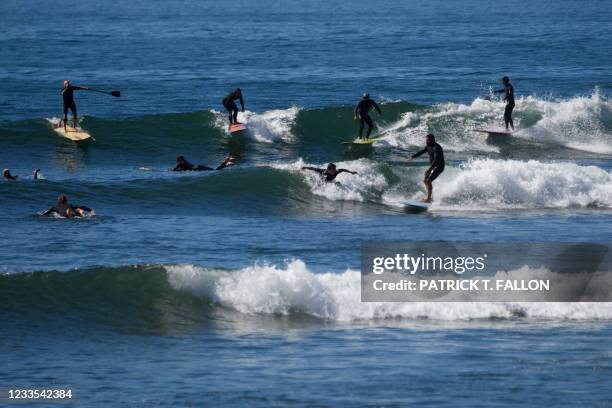 Surfers and a paddle boarder ride waves in the Pacific Ocean while surfing at the "Surfrider" Malibu Lagoon State Beach on June 9, 2021 in Malibu,...