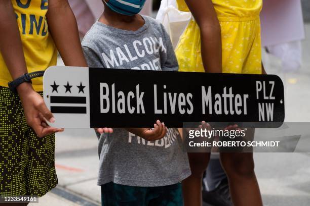 Children pose for a photograph with a Black Lives Matter Plaza street sign at Black Lives Matter Plaza in Washington, DC, on June 19 during a...