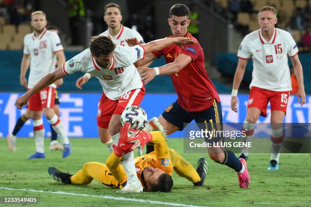 Poland's goalkeeper Wojciech Szczesny tries to grab the ball as Poland's defender Bartosz Bereszynski challenges Spain's midfielder Ferran Torres...