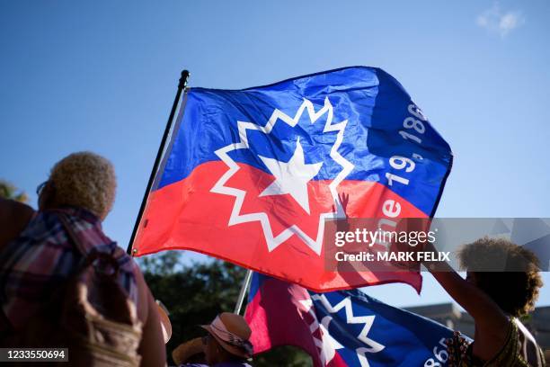 People carry a Juneteenth flag as they march during a Juneteenth re-enactment celebration in Galveston, Texas, on June 19, 2021. - The US on June 17...