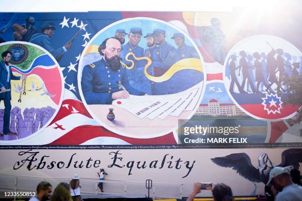 People take pictures next to a mural during a Juneteenth celebration in Galveston, Texas, on June 19, 2021. - The US on June 17 designated Juneteenth...