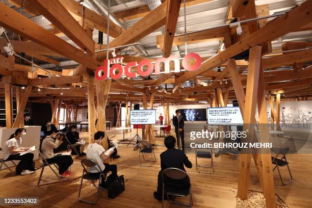 An employee of Japanese telecom provider NTT Docomo, one of the sponsors of the 2020 Tokyo Olympic Games, speaks in the "Village Plaza", during a...