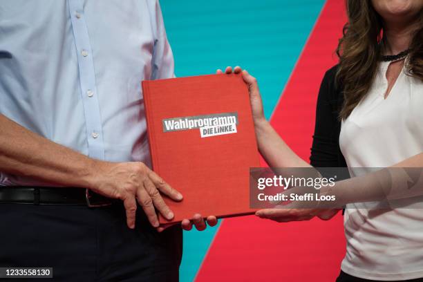 Janine Wissler and Dietmar Bartsch, lead candidates of the left-wing Die Linke political party, hold a book with the the party program which was...