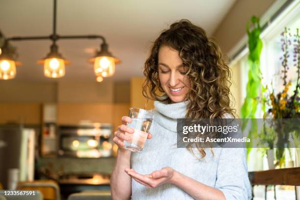 mujer tomando suplementos diarios o medicamentos - vitaminas fotografías e imágenes de stock