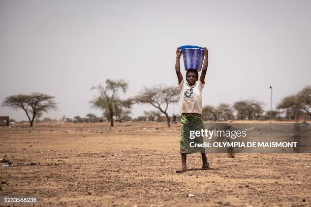 Child carries a bucket of water in Goudebou, a camp that welcomes more than 11,000 Malian refugees in northern Burkina Faso, on International Refugee...