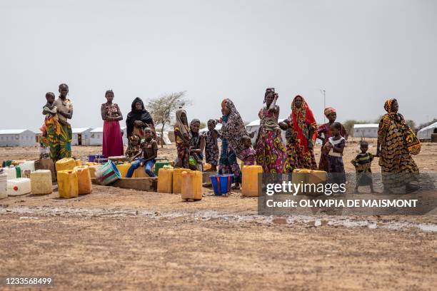 Women queue at the water pump in Goudebou, a camp that welcomes more than 11,000 Malian refugees in northern Burkina Faso, on International Refugee...
