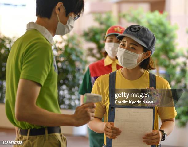 Universal Studios Japan staff member has her temperature checked before receiving a COVID-19 vaccine in Osaka on June 21 under the theme park's mass...