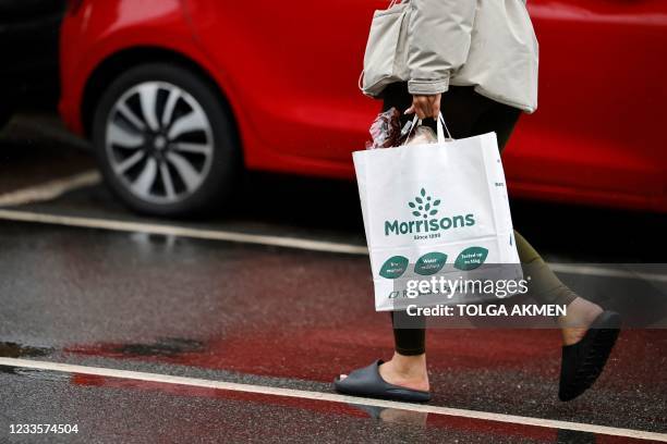 Customer carries their shopping in a paper bag outside a Morrisons supermarket in Stratford, east London on June 21, 2021. - Shares in British...