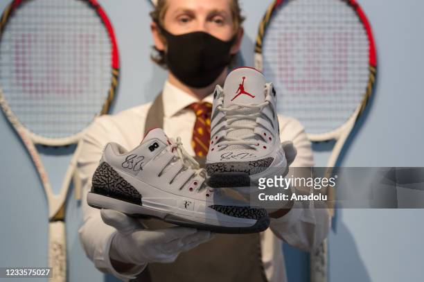 Staff member holds Roger Federer's signed tournament Air Jordans from 2014 US Open ) during a photo call for 'The Roger Federer Collection: Sold to...