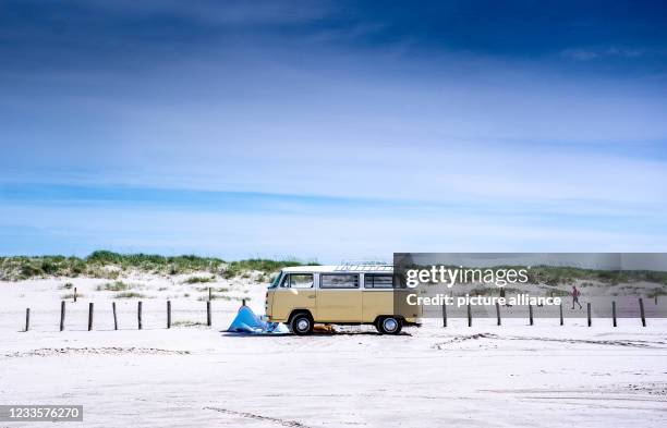 June 2021, Schleswig-Holstein, St. Peter-Ording: Campers park with a historic VW bus on the beach of St. Peter-Ording. Photo: Axel Heimken/dpa