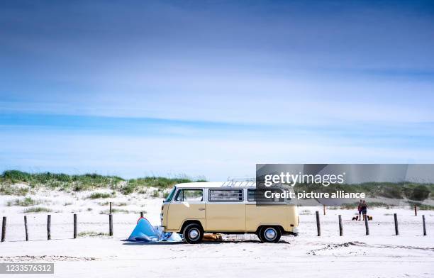 June 2021, Schleswig-Holstein, St. Peter-Ording: Campers park with a historic VW bus on the beach of St. Peter-Ording. Photo: Axel Heimken/dpa