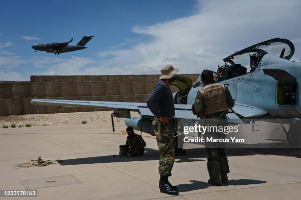 With a U.S. Air Force transport plane in the background, an Afghan A-29 pilot confers with his maintainers after a mission, at Kandahar Airbase in...