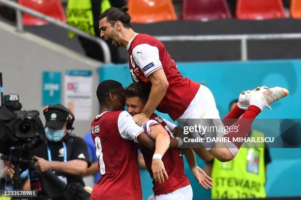 Austria's midfielder Christoph Baumgartner celebrates with Austria's defender Aleksandar Dragovic and Austria's defender David Alaba after scoring...