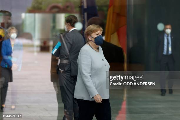 German Chancellor Angela Merkel is seen behind glass as she waits for the arrival of the European Commission President at the Chancellery in Berlin...