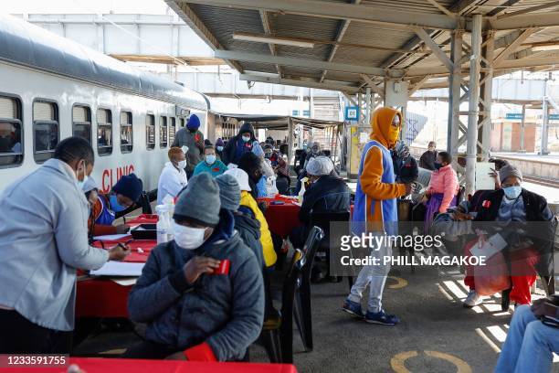 Patients register outside the Transnet-Phelophepa Healthcare Train to receive healtcare at the Dube Station in Soweto, on June 22, 2021. - The...