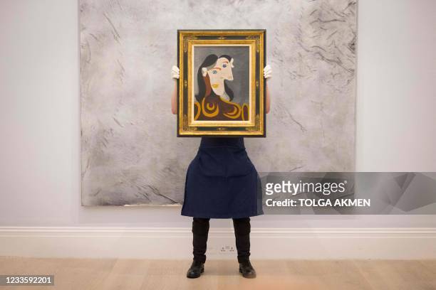 Gallery worker poses with an artwork entitled Buste de femme à la robe brune by Spanish painter Pablo Picasso during a photocall at the preview of...