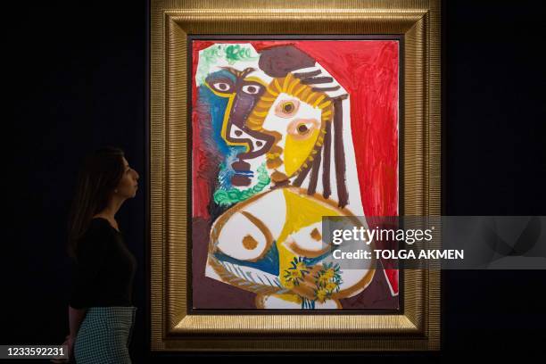 Gallery worker poses with an artwork entitled Homme et femme au bouquet by Spanish painter Pablo Picasso during a photocall at the preview of...