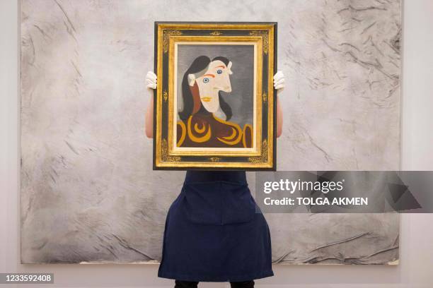 Gallery worker poses with an artwork entitled Buste de femme à la robe brune by Spanish painter Pablo Picasso during a photocall at the preview of...