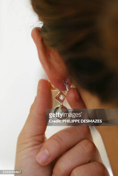 Une cliente essaye, le 17 juin 2002, une boucle d'oreille en perle de couleur dans la joaillerie Fred du 7 place Vendôme à Paris. Ce célèbre...