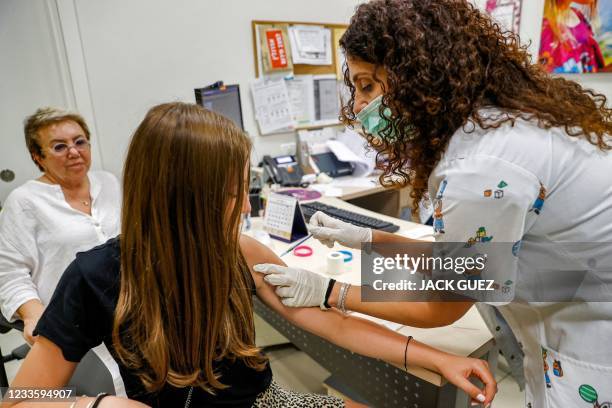 Teenage girl receives a dose of the Pfizer/BioNTech Covid-19 vaccine at the Clalit Healthcare Services in the Israeli city of Holon near Tel Aviv on...