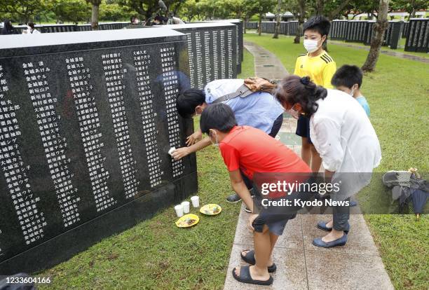 Family member of a victim in the Battle of Okinawa pours water on a monument at the Peace Memorial Park in Itoman in Okinawa Prefecture, southern...