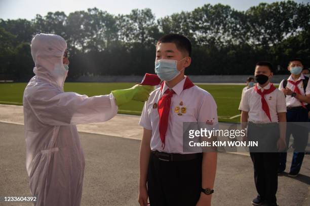 Pupil has his temperature taken as part of anti Covid-19 procedures before entering the Pyongyang Secondary School No. 1 in Pyongyang on June 22,...