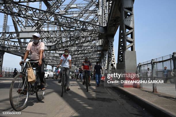 Commuters cross the Howrah Bridge on their bicycles as the state government suspended regular public transport during a lockdown imposed to curb the...