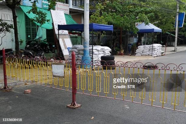 Makeshift barriers erected by the military and sand bags are seen in front of a government sub-district office along a road in Mandalay on June 23 as...